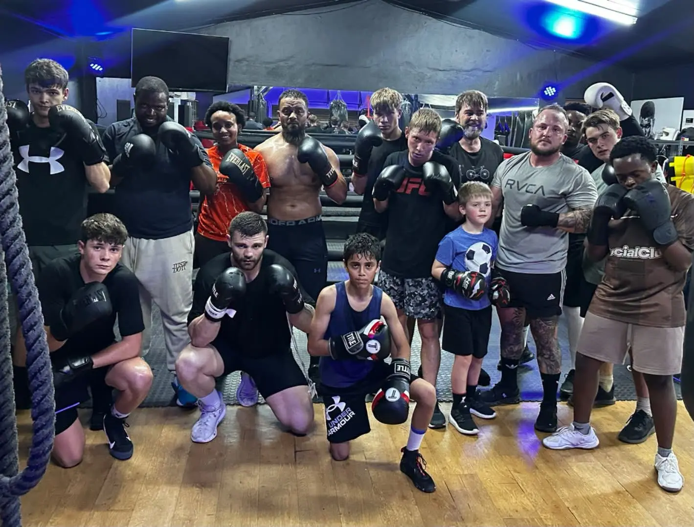 Large class photo with gloves up under the gym lights