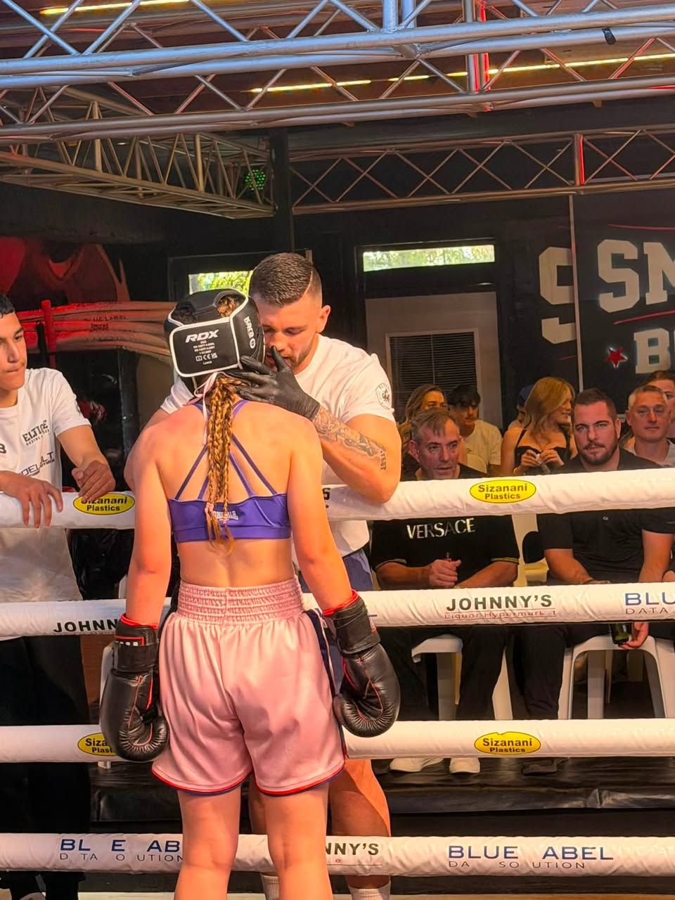 Coach fitting headgear on a fighter at a fight night